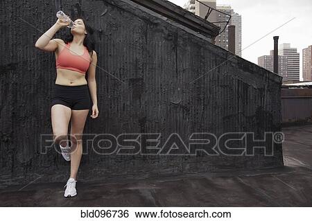 Woman in sportswear drinking water on rooftop View Large Photo Image Stock Photograph - Woman in sportswear drinking water on rooftop. Fotosearch
