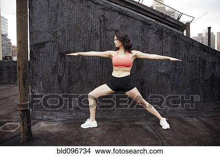Picture - Woman practicing yoga on rooftop. Fotosearch