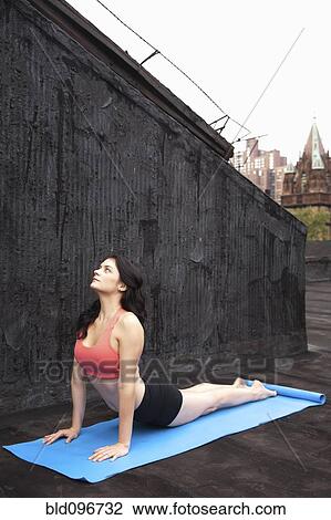 Stock Image - Woman practicing yoga on rooftop. Fotosearch