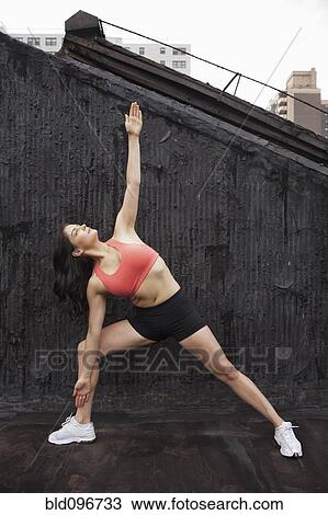 Stock Image - Woman practicing yoga on rooftop. Fotosearch