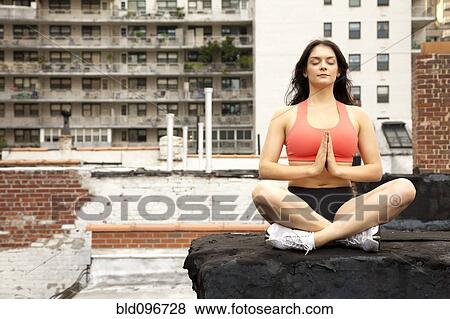 Stock Photo - Woman practicing yoga on rooftop. Fotosearch
