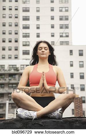Stock Photo - Woman practicing yoga on rooftop. Fotosearch
