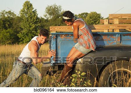 Picture - Woman watching boyfriend pushing truck. Fotosearch
