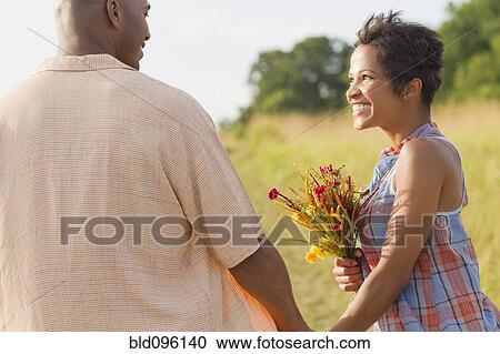 Woman with flowers holding hands with husband View Large Photo Image Stock Image - Woman with flowers holding hands with husband. Fotosearch