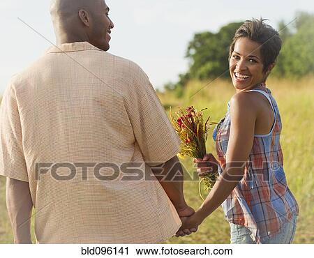 Stock Image - Woman with flowers holding hands with husband. Fotosearch