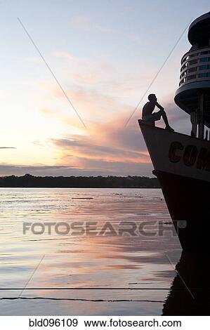 Young man sitting on boat at sunset View Large Photo Image Stock Photo - Young man sitting on boat at sunset. Fotosearch