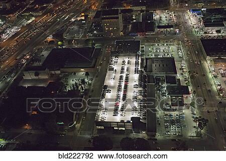 Stock Image - Aerial view of rooftop parking lot lit up at night. Fotosearch