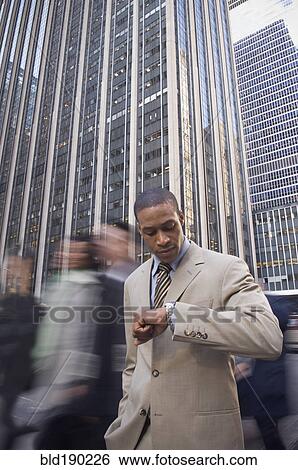 Stock Photograph - African American businessman checking watch. Fotosearch