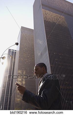 Stock Photograph - African American businessman looking at cell phone. Fotosearch