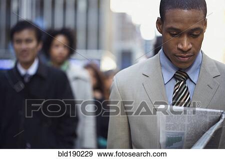 Stock Photo - African American businessman reading newspaper. Fotosearch