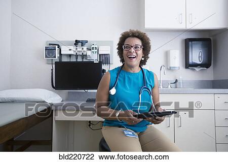 Stock Image - African American doctor holding digital tablet. Fotosearch