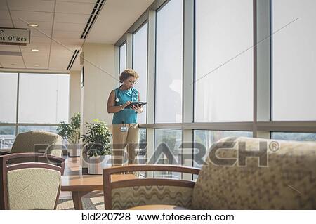 Stock Photo - African American doctor using digital tablet at window. Fotosearch