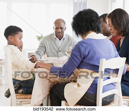 Stock Image - African American family praying before meal. Fotosearch