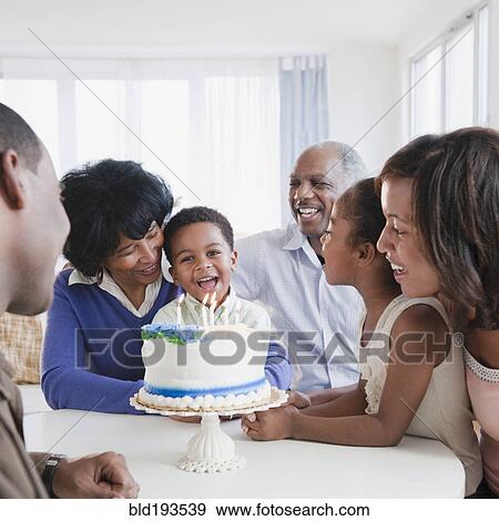 Stock Photo - African American family watching grandson blow out birthday candles. Fotosearch