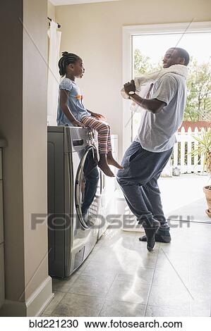 Stock Image - African American father and daughter doing laundry. Fotosearch