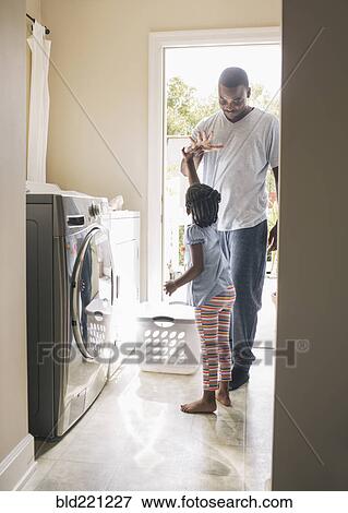 Stock Photo - African American father and daughter doing laundry. Fotosearch
