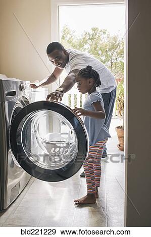 Stock Photo - African American father and daughter doing laundry. Fotosearch