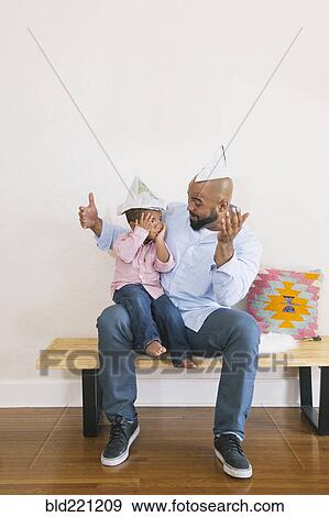 Stock Photo - African American father and son playing on bench. Fotosearch