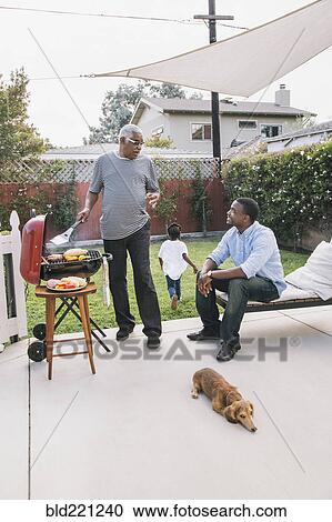 Stock Image - African American father and son talking at barbecue. Fotosearch