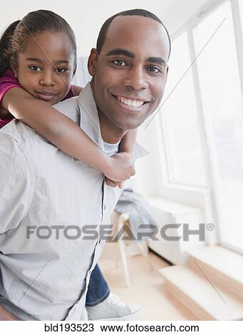 Stock Image - African American father carrying daughter on back. Fotosearch