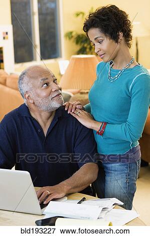 Stock Photo - African American father paying bills while daughter looks on. Fotosearch