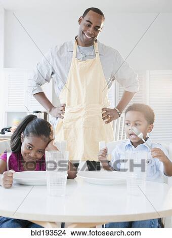 Picture - African American father preparing dinner for children. Fotosearch
