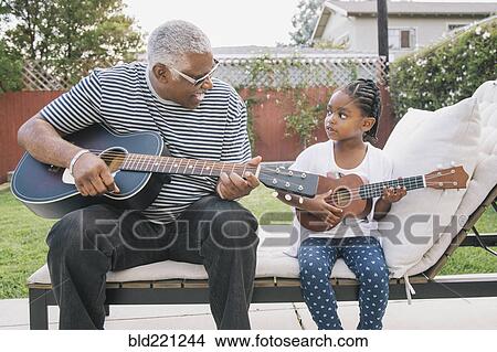 Picture - African American grandfather teaching granddaughter to play guitar. Fotosearch