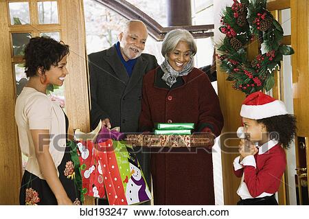 Stock Photo - African American grandparents arriving with Christmas gifts. Fotosearch