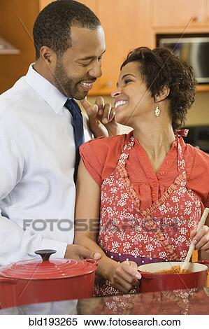 Stock Photography - African American husband greeting wife in kitchen. Fotosearch