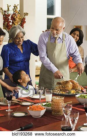 Stock Photo - African American man carving Thanksgiving turkey. Fotosearch