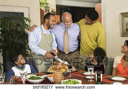 Stock Photo - African American man carving Thanksgiving turkey. Fotosearch