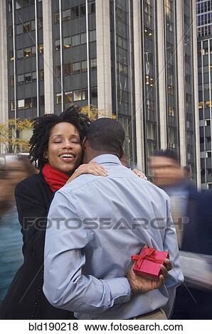 Stock Photo - African American man surprising wife with gift. Fotosearch