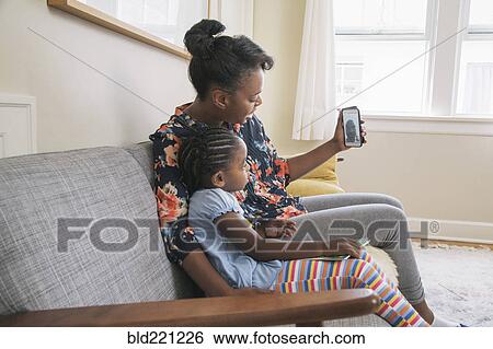 Stock Photograph - African American mother and daughter video chatting on cell phone. Fotosearch