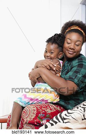 Stock Image - African American mother holding daughter on lap. Fotosearch