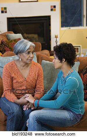 Stock Photo - African American mother talking with daughter in living room. Fotosearch