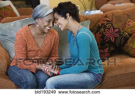 Stock Photo - African American mother talking with daughter in living room. Fotosearch