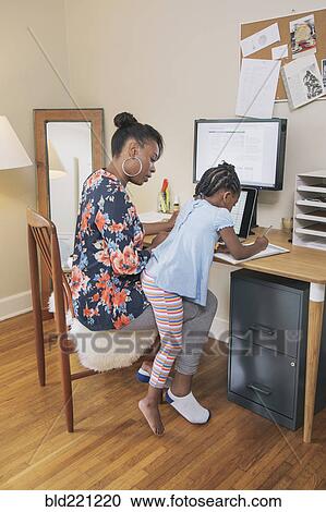 Stock Image - African American mother with daughter working from home. Fotosearch