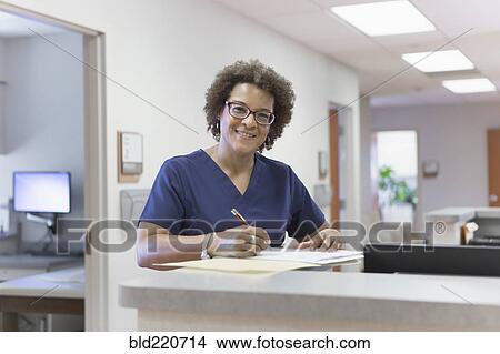 Picture - African American nurse writing in hospital. Fotosearch