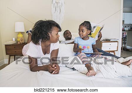 Stock Photography - African American parents and daughter on bed. Fotosearch