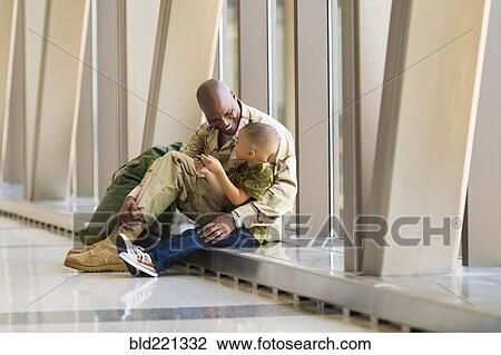 Stock Image - African American soldier and son talking in airport. Fotosearch
