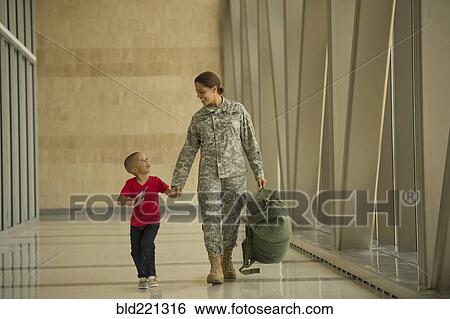 Stock Photograph - African American soldier and son walking in airport. Fotosearch