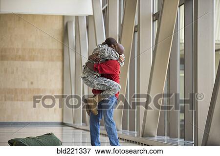 Stock Photo - African American soldier hugging husband in airport. Fotosearch