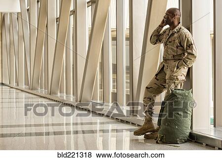 Stock Photo - African American soldier talking on cell phone in airport. Fotosearch