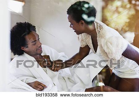 Stock Photo - African American woman kneeling on bed with husband. Fotosearch