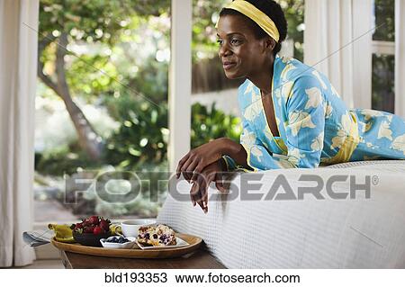 Stock Image - African American woman laying on bed. Fotosearch