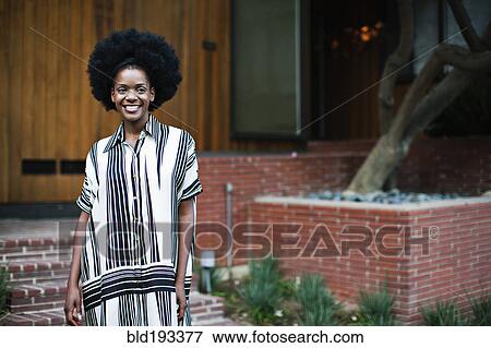 Stock Photo - African American woman standing outside house. Fotosearch