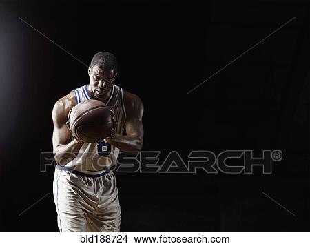 Picture - African basketball player holding basketball. Fotosearch