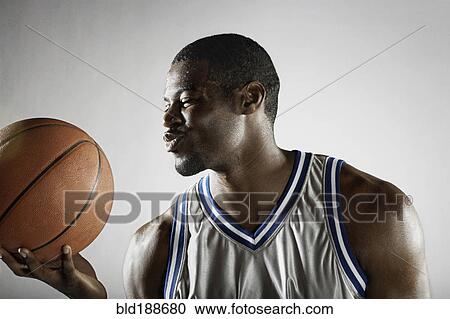 Stock Image - African basketball player holding basketball. Fotosearch