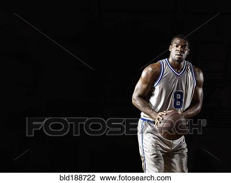 Stock Image - African basketball player holding basketball. Fotosearch