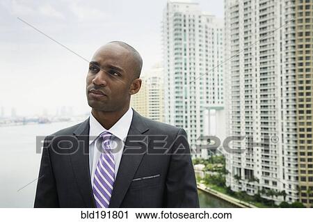Stock Image - African businessman looking pensive on urban balcony. Fotosearch